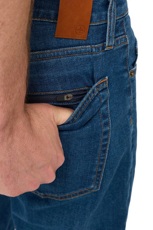 Hand opening the hidden zipper back pocket on men's vintage indigo tailored travel jeans