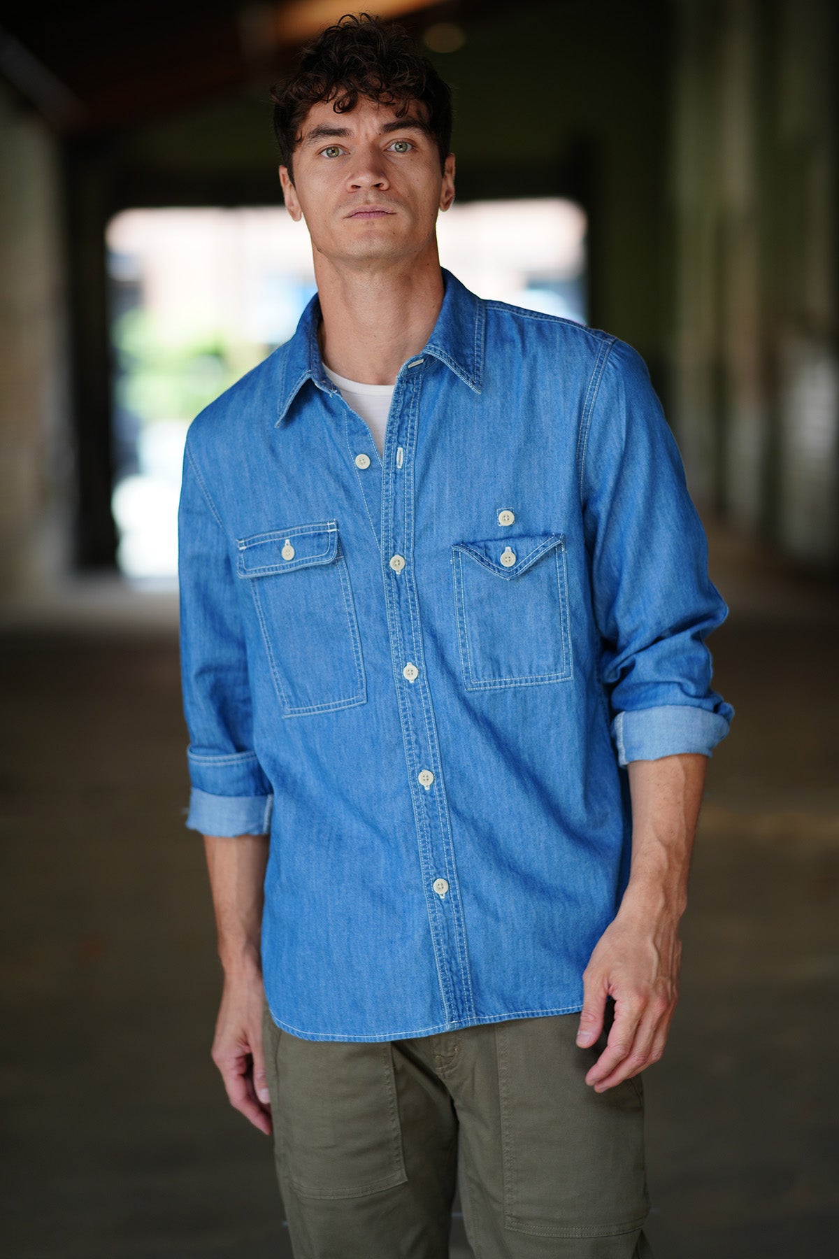 Man wearing a blue chambray shirt on a white background.