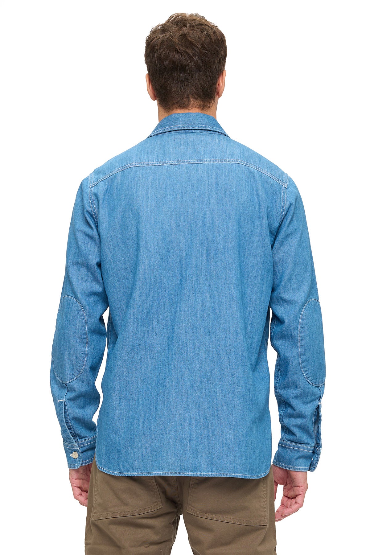 Man wearing a blue chambray shirt on a white background. 