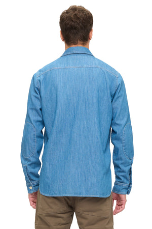 Man wearing a blue chambray shirt on a white background. 